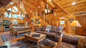 A log cabin interior with a dining area, a leather sofa, a wooden coffee table, and a fur rug. - TEXAS 2 STEP Luxury Log Cabin at the Entrance to Beavers Bend State park (Broken Bow)