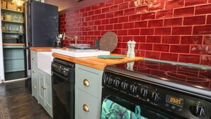 A kitchen with a red brick backsplash, a wooden countertop, and a stove. - Dreytop (Ryde)