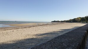 A wide sandy beach with a clear sky, a calm sea, and a line of trees in the background. - Dreytop (Ryde)