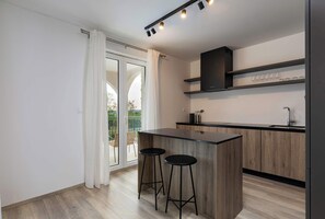 A modern kitchen with a bar area, wooden cabinets, and a sliding glass door to a balcony.
