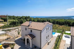Ein zweistöckiges Haus mit Ziegeldach, Schwimmbad und Meerblick.
