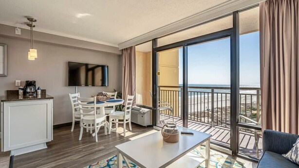 A modern hotel room with a balcony, a dining area, and a living space. - Ocean Views For Miles!! - Caravelle Resort #810 (Myrtle Beach)