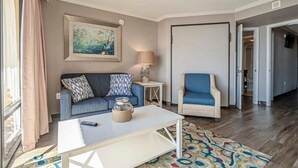 A living room with a sofa, armchair, coffee table, lamp, and artwork. - Ocean Views For Miles!! - Caravelle Resort #810 (Myrtle Beach)