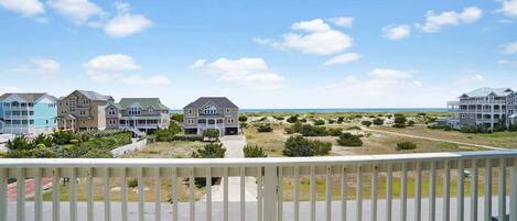 A coastal residential area with multiple houses, a clear sky, and a view of the ocean.