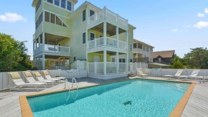 Um edifício com vários andares e área de piscina, incluindo piscina, espreguiçadeiras e um deck.