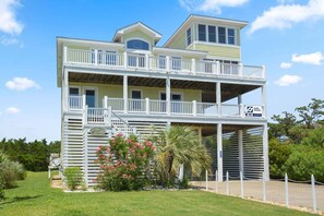 Une maison à deux étages située en bord de mer, dotée de plusieurs balcons, d’une antenne parabolique et d’une enseigne indiquant « Surf Sound ».