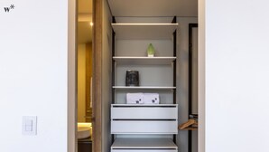 Un bagno moderno e minimalista con un mobile lavabo bianco, un porta asciugamani e un'unità con cassetti e una ventola.