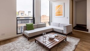 Un soggiorno moderno con un divano componibile, un tavolino in legno e un'ampia finestra con vista sulla città.