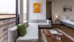 Un soggiorno moderno con un'ampia finestra, un divano, un tavolino da caffè e opere d'arte alle pareti.