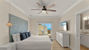 A bedroom with a bed, dresser, ceiling fan, and a view through a door. - Spacious Beachfront 3 Bedroom! (Destin)