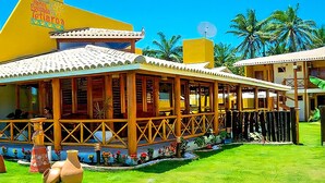 A hotel with a covered outdoor area, a swimming pool, and a garden with large pottery sculptures. - Hotel Tetiaroa (Maraú)