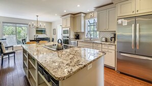 Una cocina moderna con encimeras de granito, electrodomésticos de acero inoxidable y una isla grande.