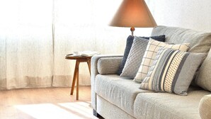 Una sala de estar acogedora con un sofá, una mesita auxiliar y una lámpara.