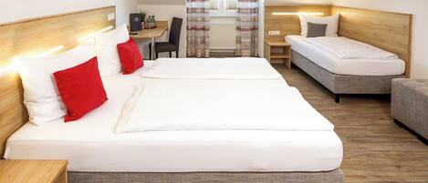 A hotel room with two beds, a small table, and a chair.
