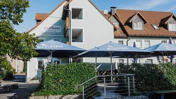 Ein Gebäude mit der Beschilderung 'Gasthaus Zur Linde' und Sonnenschirmen, die 'Mönchsöli' zeigen.