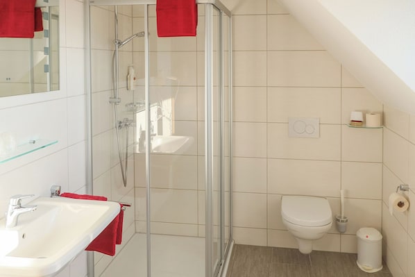A modern bathroom with a glass shower enclosure, a white sink, and a toilet. - Gasthaus zur Linde (Dombuehl)