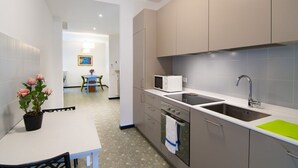 Una cocina moderna con encimera blanca, electrodomésticos de acero inoxidable y tabla de cortar verde.