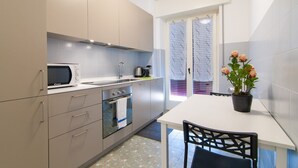 Una cocina moderna con microondas, estufa y lavabo. Hay una mesa de comedor con sillas y una planta en maceta.