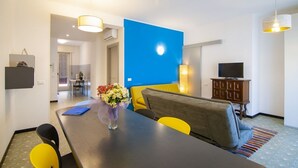 Una sala moderna con comedor, una pared azul de acento, un sofá, un televisor y un mueble.