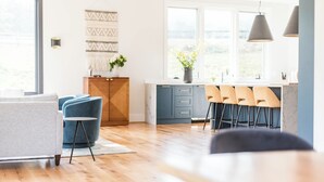 Een moderne keuken met houten vloer, blauwe kastjes en een eethoek met een ronde tafel en stoelen.