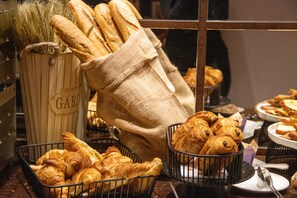 Une variété de produits de boulangerie, notamment des croissants et des baguettes, présentés dans des paniers et sur des assiettes.