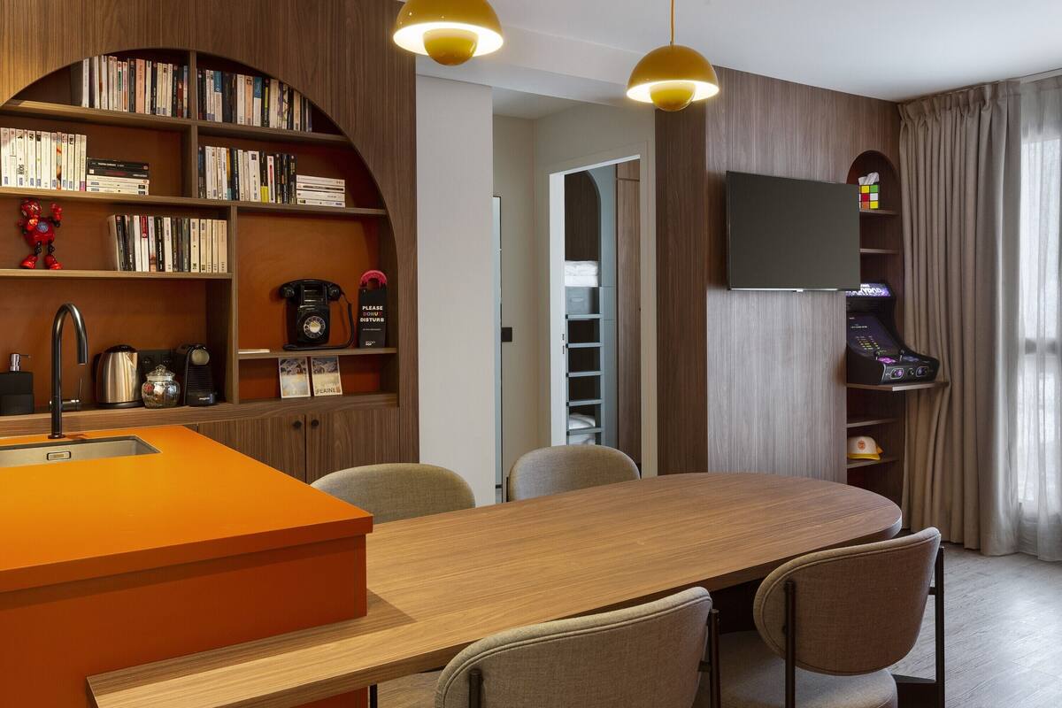 Une cuisine moderne dotée d’un îlot central en bois, de bibliothèques intégrées et d’un téléviseur à écran plat.