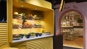 Un camion-restaurant jaune où sont exposés divers fruits et légumes sur des étagères et des tables.
