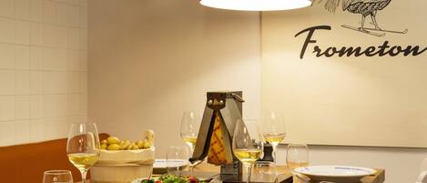 A dining table set with plates, glasses, a cheese slicer, a bowl of salad, and various meats.