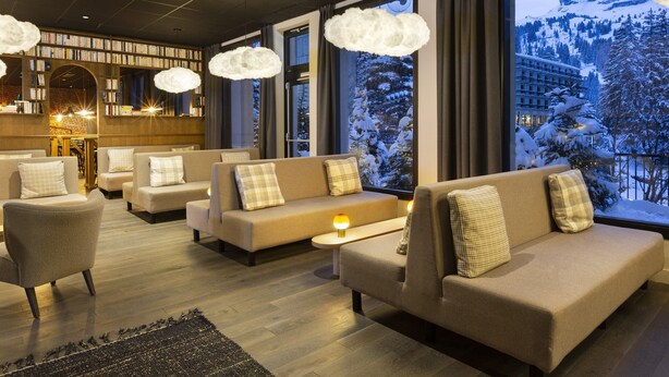 Un hall d’hôtel accueillant, avec des canapés et des fauteuils, une cheminée et une bibliothèque.