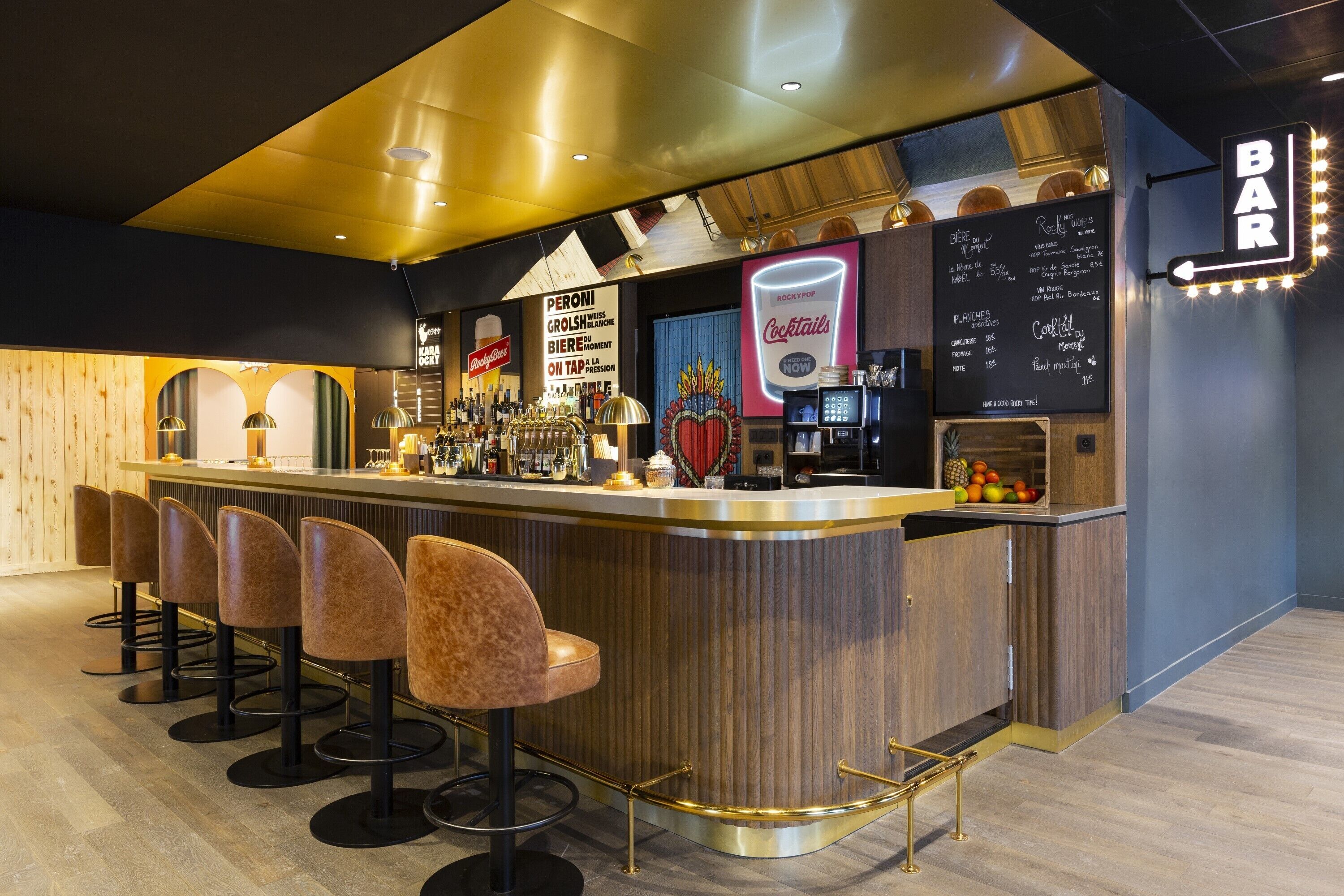 A bar area with a counter, stools, and a neon sign.