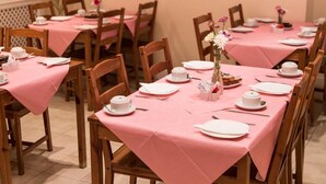 A dining area with pink tablecloths and wooden chairs. - Europa House (London)