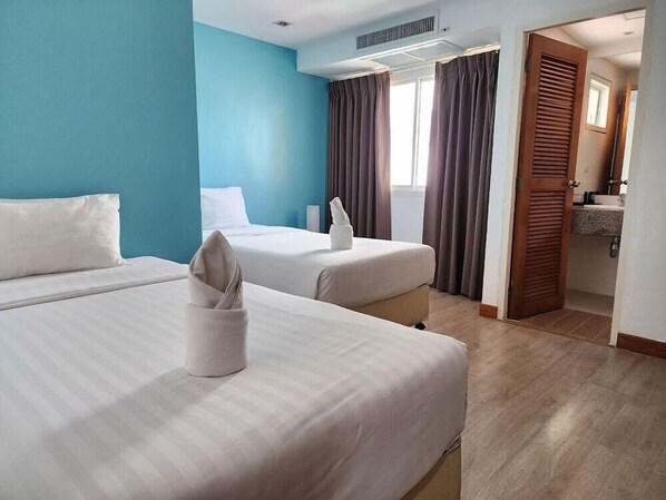 A hotel room with two beds, a bathroom, and a view of the outside. - By Deeatjomtien (Pattaya)