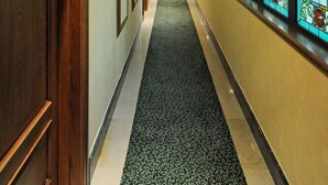 A hotel hallway with a carpeted floor, wooden doors, and stained glass windows. - Hotel Julia (Madrid)