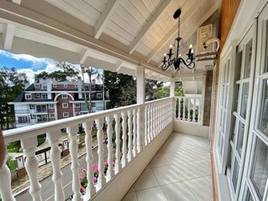 Een balkon met een witte reling, een kroonluchter en uitzicht op een meerhoog gebouw.