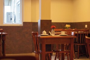 Een eethoek met een houten tafel, stoelen en een vaas met bloemen.