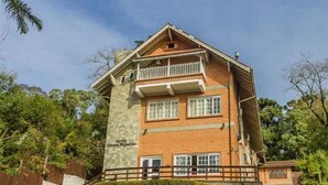 A two-story hotel with a brick facade, a balcony on the upper floor, and a well-maintained garden in front. - Laponia Hotel Gramado (Gramado)
