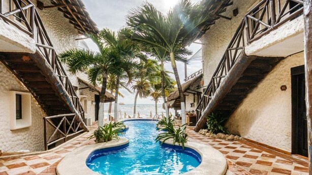 A pool area with a checkered floor, palm trees, and a staircase leading to a balcony. - Hotel Mimi Del Mar (Playa del Carmen)
