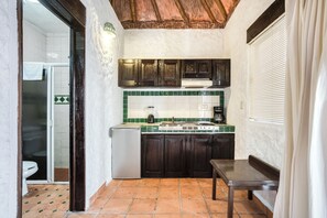 A compact kitchen with dark wooden cabinets, a green tiled backsplash, and a small countertop. - Hotel Mimi Del Mar (Playa del Carmen)