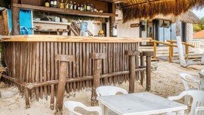 A beachside bar area at Hotel Mimi del Mar with wooden furniture and a thatched roof. - Hotel Mimi Del Mar (Playa del Carmen)