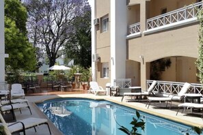 Ein Poolbereich mit Liegestühlen, einem Tisch und Sonnenschirmen.