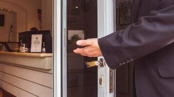 Una persona abre una puerta con llave, mostrando un área de recepción con mostrador y planta.