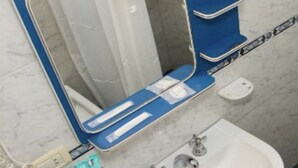Une salle de bain avec un miroir, un lavabo et une étagère bleue.