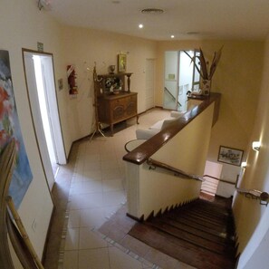 A staircase with a wooden handrail leading to a landing. There is a small table with a vase and a picture frame on the landing.