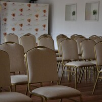 Filas de sillas color beige con detalles dorados dispuestas en una sala de conferencias.