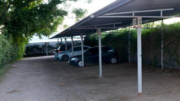 A covered parking area with two cars parked under a roof structure.