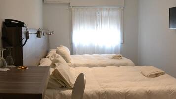 Habitación de hotel con cama, escritorio, silla y ventana con cortinas.