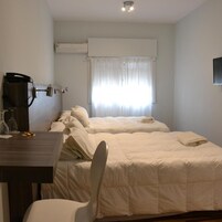 Habitación de hotel con cama, escritorio, silla y ventana con cortinas.