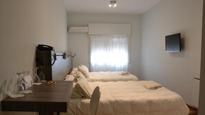 Een hotelkamer met een bed, een bureau met stoel, een televisie en een airconditioning.