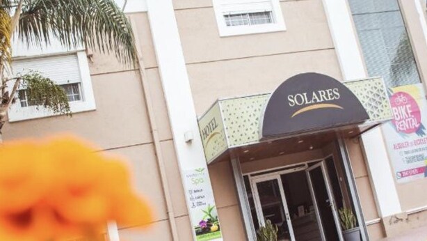 Un hôtel appelé « SOLARES », avec une enseigne, un panneau indiquant un service de location de vélos et une publicité pour un spa.