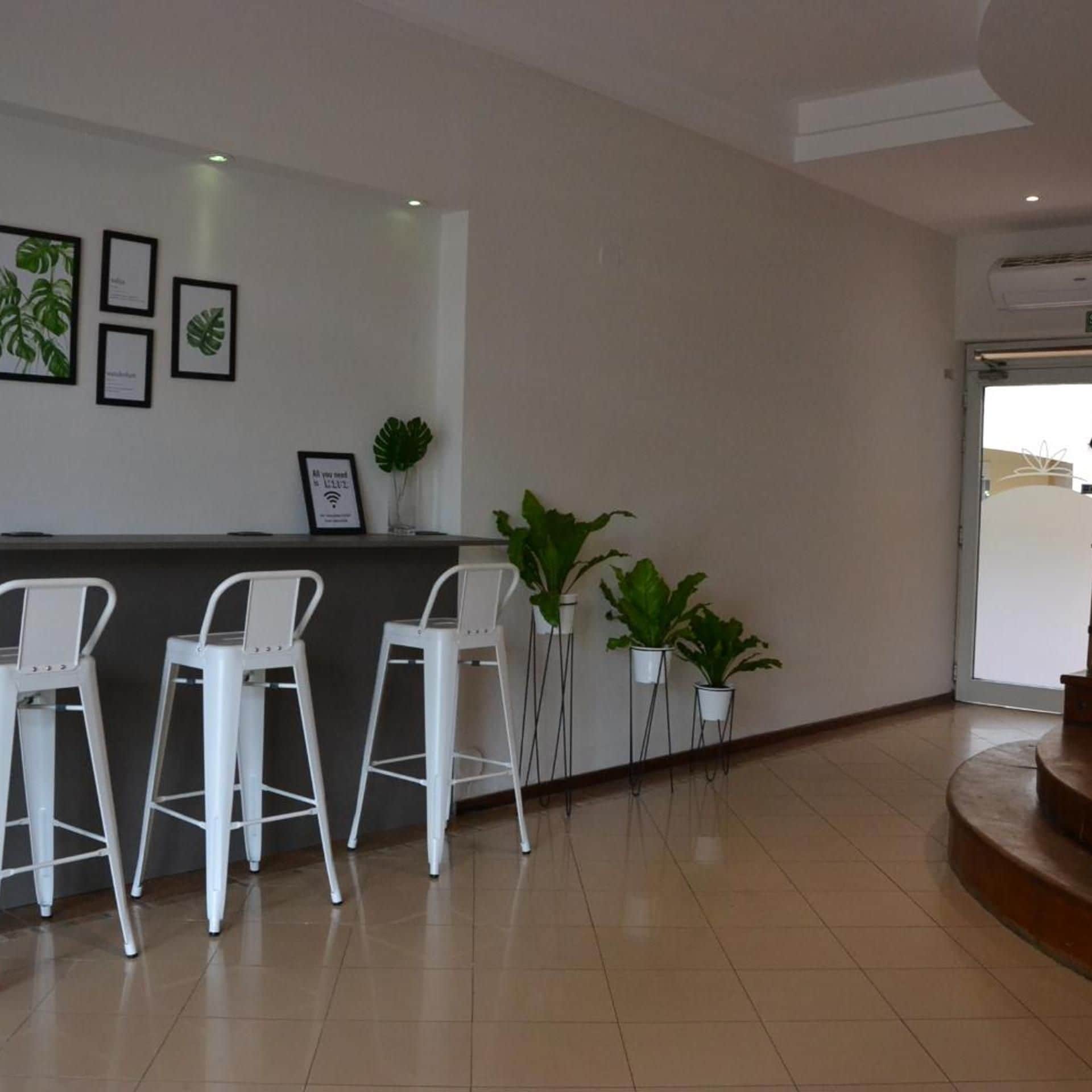 A reception area with a counter, framed botanical prints, and potted plants.